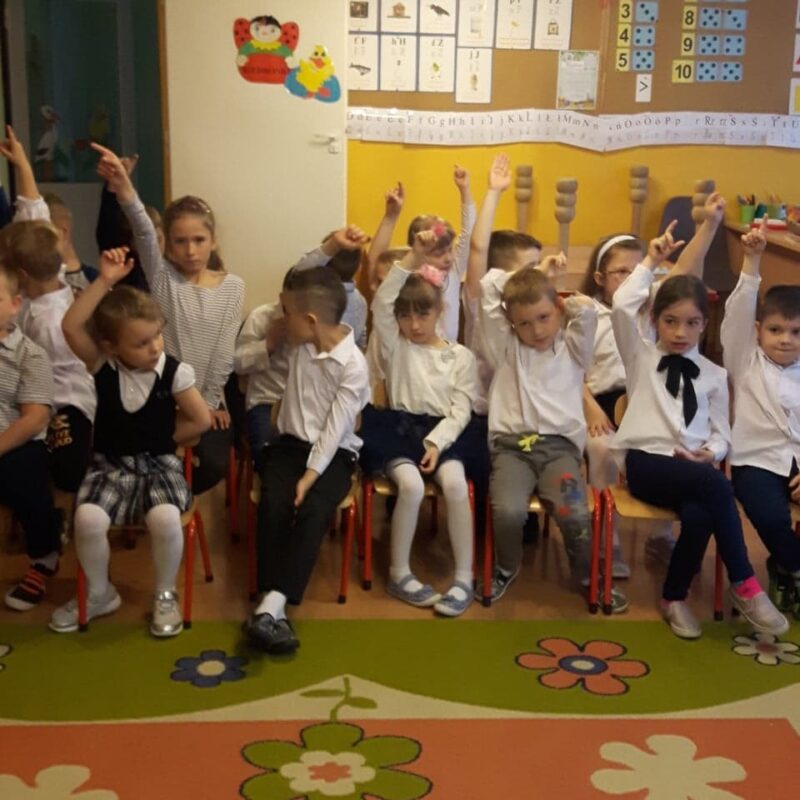 Dzieci podnoszą ręce by zgłosić się do odpowiedzi.